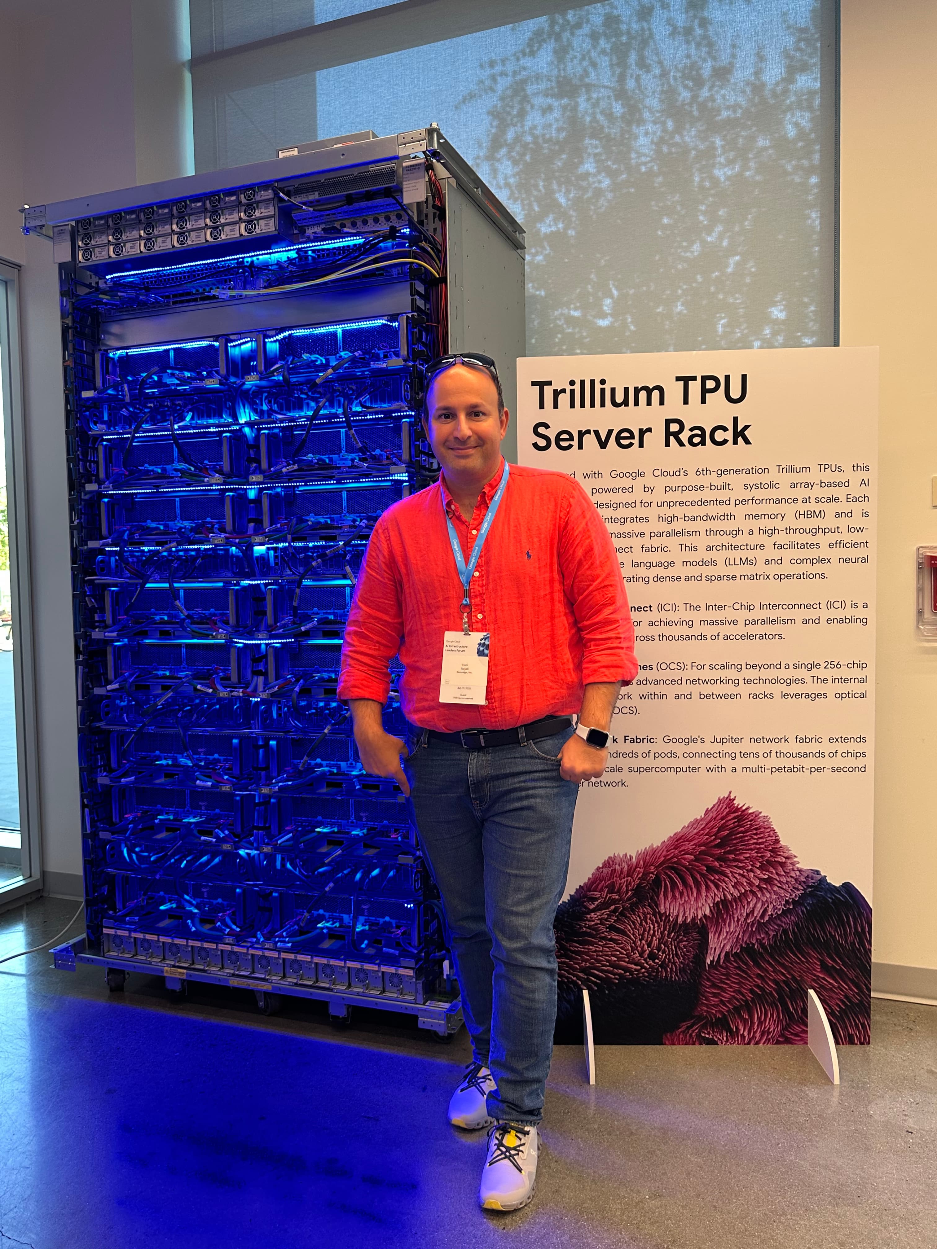 Hadi Nejati standing beside a Trillium TPU server rack.